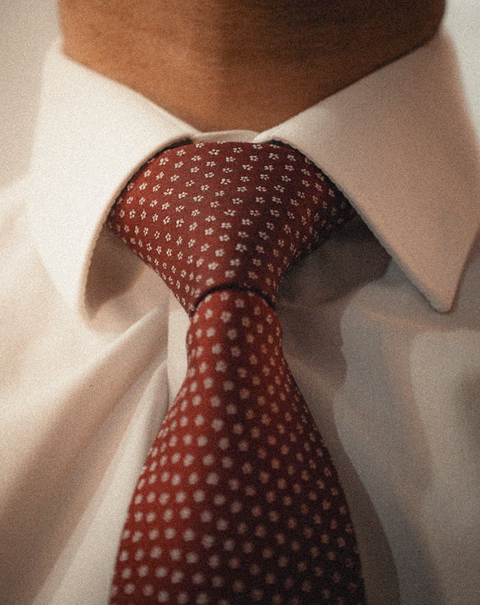 Elegant close-up of a red polka dot tie paired with a crisp white shirt, showcasing formal attire.